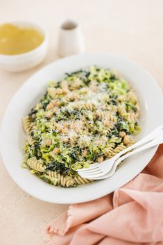 a white plate topped with pasta and broccoli next to a bowl of sauce