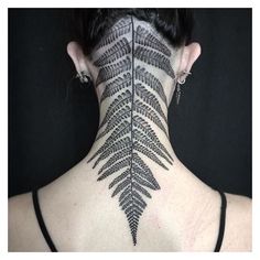 the back of a woman's neck is covered in black and white leaves, which are