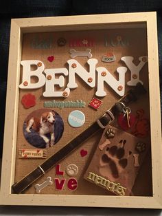 a dog is sitting in a shadow box with its paw prints and name on it