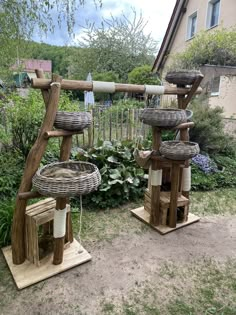 two wooden bird feeders sitting on top of each other in the grass next to a house