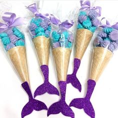 three ice cream cones with purple and blue flowers in them on a white tablecloth