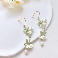 🍀 Size: 7.3x1.4 cm 🍀 Material: Freshwater Pearl, 14K Gold Plated Sterling Silver Hook, Brass (✨Hypoallergenic Hook✨) Description 🌸 Add a touch of delicate elegance to your look with these extremely intricate and delicate Lily of the Valley earrings. These ethereal dangle earrings feature freshwater pearls and the iconic bell-shaped blooms of the Lily of the Valley flower, creating a romantic and sophisticated look. Each flower is flexibly attached to the stem, creating a lifelike vivid look.  These earrings are perfect for brides-to-be or as a special gift for your bridesmaids. They also make for a great addition to any formal or special occasion outfit. Please note that freshwater pearls are naturally unique and may exhibit slight variations in size, shape, and colour. 🌸 ⭐️ Shop more Green Round Flower Earrings For Wedding, Green Flower Wedding Earrings, Green Flower Earrings For Wedding, Flower Shaped Wedding Earrings With Ear Wire, Pierced Flower Wedding Earrings, Flower Shaped Wedding Earrings, Pierced Flower Shaped Wedding Earrings, Wedding Flower Dangle Earrings Pierced, Delicate Green Flower Earrings For Wedding