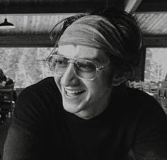 a man wearing glasses sitting at a table with food in front of him and smiling