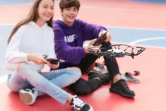 two people sitting on the floor with remotes in their hands and one holding a camera