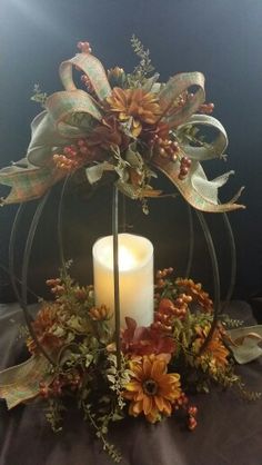 a candle is sitting on top of a table with flowers and leaves around it in front of a black background