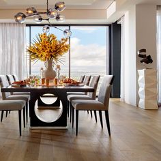 a dining room table with chairs and a vase filled with flowers on top of it