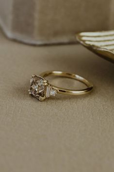 a gold ring with two diamonds sitting on top of a table next to a plate