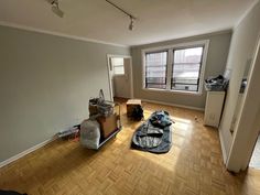 an empty room with hard wood flooring and bags on the floor in front of it