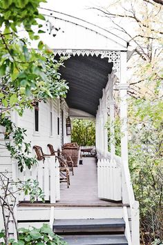 a porch with steps leading up to the front door and covered in white railings