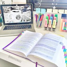 an open book sitting on top of a desk next to a laptop