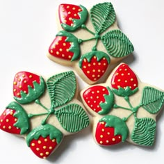 four decorated cookies with green icing and strawberries