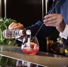 the bartender is pouring drinks into glasses on the bar counter with garnishes