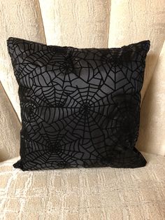 a black pillow sitting on top of a white chair next to a wall with spider webs