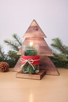 a small wooden christmas tree sitting on top of a table next to some pine cones