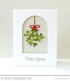 a white card with a red bow on it and some green leaves in the middle