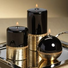 two black candles sitting on top of a metal tray