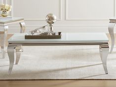 a glass coffee table sitting on top of a wooden floor next to a white rug