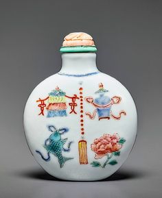 a white vase with colorful designs on the top and bottom, sitting against a gray background