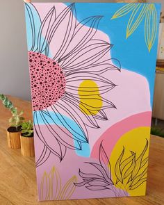 a painting on a wooden table next to a potted plant