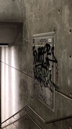 an elevator with graffiti on the wall and metal handrails in front of it