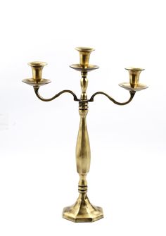 a three - light brass candelabra with four candles in the middle, on a white background