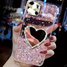 a woman's hand holding up a phone case with a heart shaped diamond on it