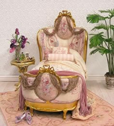 a fancy bed with pink and gold decor in a room next to a potted plant