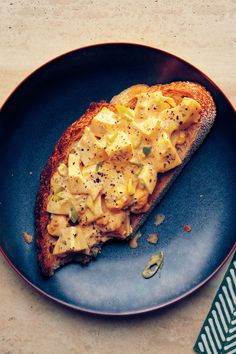 a piece of bread with macaroni and cheese on it sitting on a blue plate