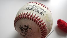 an old baseball sitting on top of a table next to some crochet hooks