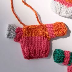 two knitted mittens are laying next to each other on a white table top