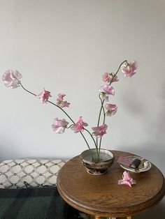 pink flowers are in a vase on a small table