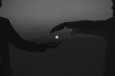 two people reaching out towards each other in the dark with their hands outstretched toward an object