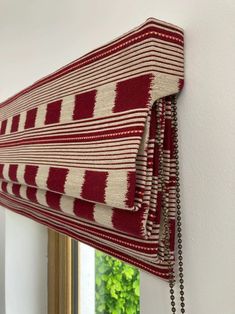 a red and white striped curtain hanging on the side of a wall next to a mirror