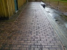 an empty brick walkway in front of a yellow building