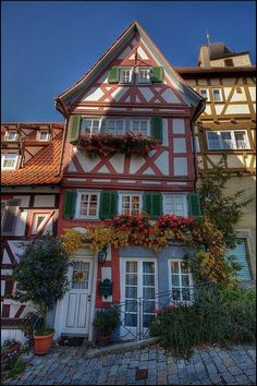 an old house with flowers on the windows