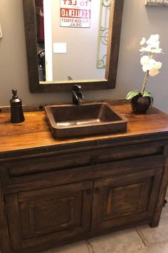 a bathroom with a sink, mirror and wooden cabinet in the corner that is made out of wood