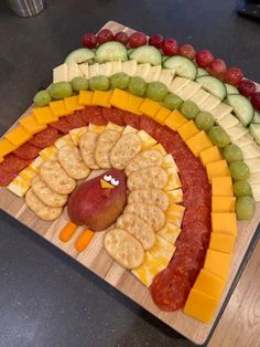 a platter with crackers, grapes, cheese and fruit arranged in the shape of a turkey