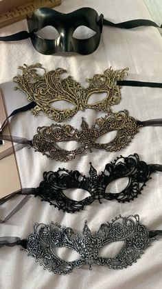 several masks are lined up on a white sheet with black and gold trimmings