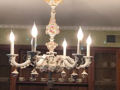 a chandelier with five lit candles hanging from it's sides in a room