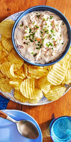 a bowl of dip surrounded by chips on a plate