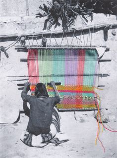 a person sitting on the ground next to a large weaving machine with colorful strips hanging from it's sides