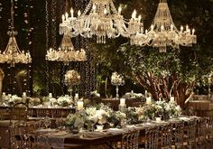 an elaborate dining room set up with chandeliers and tables covered in white flowers