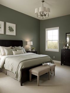 a bedroom with green walls and white carpeted flooring, a large bed is flanked by two framed pictures on the wall