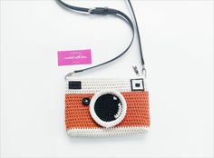 an orange and white crocheted camera purse