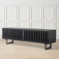 a black bench sitting on top of a hard wood floor next to a white wall