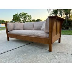 a wooden couch sitting on top of a sidewalk