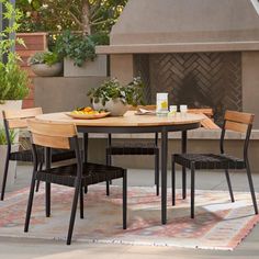 an outdoor table with chairs around it on a rug in front of a fire place