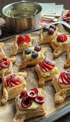 several pastries are arranged on a baking sheet with berries and cream toppings in the shape of stars