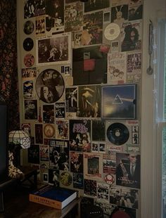 a wall covered with various records and cds in a living room next to a window