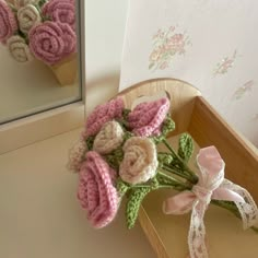 a bouquet of crocheted flowers sitting on top of a wooden tray next to a mirror